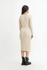 Vestido midi color crema, tejido en punto acanalado, con escote cruzado en V, mangas largas y lazo ajustable en la cintura.
