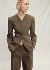 Blazer de corte oversize confeccionado en tejido mezcla de lino, con cuello de pico, cierre frontal y mangas largas con efecto globo. Presenta dos bolsillos de ribete laterales y abertura posterior en el bajo.