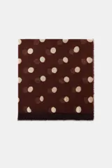 Pañuelo rectangular de lana con estampado de lunares en tonos claros sobre fondo marrón oscuro. Presenta bordes desflecados y una franja lisa en uno de los extremos.