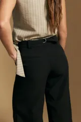 Pantalón de vestir negro de corte ancho y tiro alto, con silueta fluida y diseño minimalista.