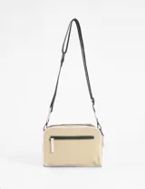 Bandolera de diseño rectangular en color verde oliva claro, con detalles de ribetes en tono rosado. Cuenta con correa ajustable, cierre principal y un bolsillo frontal con cierre, además de un pequeño aplique metálico decorativo en la parte inferior.