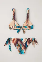 Conjunto de bikini con estampado floral en tonos azules, naranjas y blancos, compuesto por un top con nudo frontal y tirantes anchos, y una bombacha vedetina ajustable con lazos en los laterales.