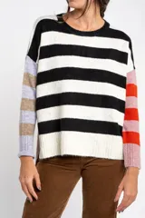 Sweater de punto con diseño a rayas horizontales en blanco y negro en el cuerpo, y mangas con bloques de color en tonos lila, beige, rosa y naranja. Presenta cuello redondo y puños acanalados.