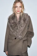 Chaqueta de corte recto confeccionada en mezcla de lana, color marrón topo. Presenta un cuello de solapa amplio con aplicación de pelo sintético desmontable, cierre frontal cruzado con botones y bolsillos laterales con solapa.