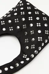 Cartera tipo hobo confeccionada en gamuza negra, con asa integrada y decorada en toda su superficie con tachas metálicas plateadas dispuestas en patrones geométricos.