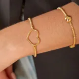 Pulsera de malla extensible en oro amarillo y blanco de 18k, con detalle de esfera central pulida.