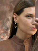 Aros tipo argolla de bronce con diseño irregular y detalles de esferas pequeñas.