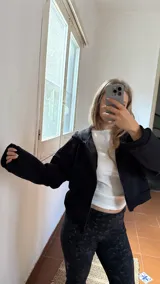 Campera de jogging negra con cierre frontal completo, capucha y bolsillos laterales. Confeccionada en tela frizada en su interior.