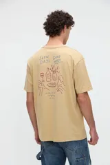 Remera de manga corta color beige, confeccionada en jersey de algodón con textura suave y calce relaxed. Presenta costuras a contratono en la espalda y un diseño estampado en la parte posterior con ilustraciones de estilo lineal y frases manuscritas.