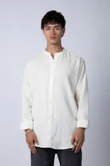 Camisa de lino color blanco con cuello mao y cierre frontal de botones. Presenta mangas largas con puños simples y un corte clásico.