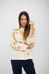 Buzo de tejido de punto con diseño estampado de flores en tonos mostaza y gris sobre fondo blanco. Presenta cuello redondo, mangas largas y corte recto.