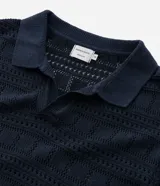 Remera polo masculina de manga corta, color azul marino, con cuello en V y diseño de textura tipo patchwork.