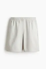 Short de felpa interlock, color gris claro, con cintura elástica con cordón oculto, bolsillos laterales y corte relajado.
