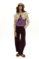 Camisa de popelina de algodón color mostaza con estampado floral blanco. Presenta un cuello amplio con terminación ondulada y encaje de algodón crudo, mangas largas y botones de nácar en el frente.