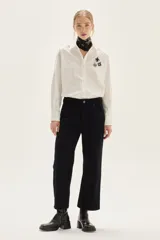 Camisa blanca de corte oversize, confeccionada en algodón, con cuello clásico y cierre frontal de botones. Presenta un bordado de corazones en el pecho.