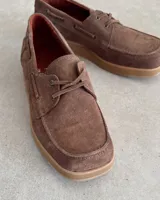Zapato náutico marrón de cuero vacuno con cordones y suela plana.