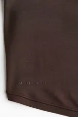 Top de yoga cropped de manga larga, confeccionado en punto modal suave, color marrón. Cuenta con un escote en V pronunciado y una tira frontal para anudar.