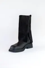 Bota de cuero negra con caña alta y detalle volcado en la parte superior. Taco bajo y puntera redondeada.