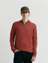 Sweater de punto color verde oliva, con cuello alto y medio cierre frontal. Presenta coderas en símil nappa y puños acanalados.