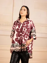 Camisa de manga corta con estampado abstracto en tonos azul marino, azul claro y blanco, y un patrón floral en el dobladillo.