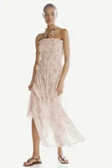 Vestido midi strapless en mezcla de viscosa, con estampado paisley en tonos rosados, azules y marrones sobre base beige. Presenta cuerpo fruncido elástico con volados en el escote y falda con corte escalonado.