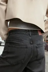 Jeans tobilleros de tiro alto, color negro lavado, con pernera recta y acabado sin costura en el ruedo. Modelo de cinco bolsillos con cierre frontal de cremallera y botón.