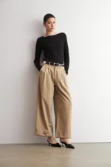 Pantalón pinzado beige de corte ancho y relajado, tiro alto, con bolsillos laterales y detalle de doblez en los bajos.