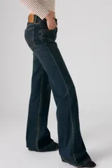 Jeans de denim azul oscuro con lavado vintage, tiro alto y corte acampanado.