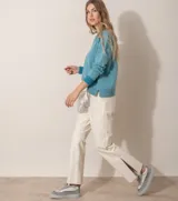 Pantalón de cuero ovino italiano en color marfil, de corte recto y tiro medio, con aberturas en el bajo de las botamangas.