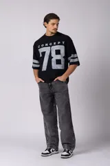 Remerón de corte oversize con cuello redondo y mangas cortas. Presenta un diseño estampado frontal con la palabra 'CONCEPT' y el número '78' en efecto desgastado, además de dos franjas horizontales en las mangas.
