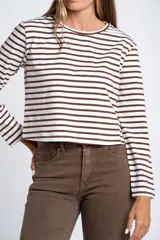 Remera de manga larga ajustada al cuerpo, con cuello redondo. Presenta un patrón de rayas horizontales anchas en color blanco y marrón oscuro.