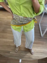 Pañuelo grande de seda o material similar, con estampado paisley en tonos beige, marrón, turquesa y amarillo mostaza, con borde liso amarillo mostaza.