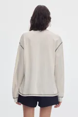 Remera de manga larga negra con bolsillo frontal en el pecho y costuras a la vista en contraste de color gris.