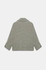 Chaqueta corta gris de tejido texturizado con cuello solapa, manga larga con trabilla, bolsillos delanteros con solapa y cierre frontal de botones metálicos.