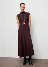 Vestido midi de color marrón oscuro, con cuello alto, diseño sin mangas y corte evasé. Presenta una costura diagonal en la cintura y cierre de botones en la parte posterior del cuello.