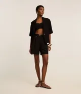 Short color visón de corte sastrero, tiro alto, con pliegues delanteros, trabillas y cinturón fino de cuero sintético.