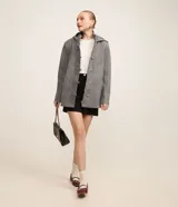 Saco corto negro de polivelour con capucha, cuello alto con cremallera, abotonado delantero cruzado, bolsillos delanteros y mangas largas.