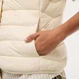 Chaleco acolchado color crema, sin mangas, con cuello mao y cierre frontal con botones a presión. Diseño ligero y corte recto.