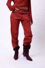 Pantalón de corte recto y largo al tobillo, con estampado de espiga en tonos oscuros y líneas rojas. Presenta tiro medio y cierre frontal.