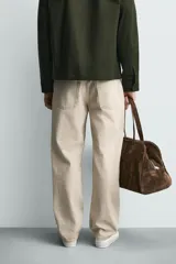 Pantalón jeans de corte recto y tiro medio, confeccionado en denim de algodón color beige con efecto lavado, bolsillos clásicos y cierre frontal con cremallera y botón.