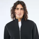 Buzo negro de corte estándar con cierre frontal completo, cuello alto y puños elásticos.