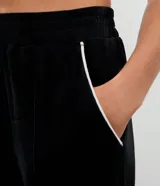 Pantalón deportivo de corte recto confeccionado en tejido de plush, con cintura elástica y detalle de piping lateral contrastante.