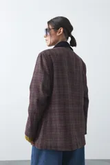 Blazer de corte relajado con estampado de cuadros tipo pied de poule en tonos rojizos y verdes. Presenta solapas clásicas en color azul oscuro y estructura definida.