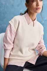 Chaleco de tejido de punto color beige claro, con cuello redondo y diseño de líneas limpias con hombros caídos y terminaciones acanaladas.