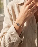 Pulsera de esferas pequeñas de plata con dije central en forma de mano de Hamsa calada.