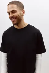 Remera negra de algodón pesado, corte holgado, con cuello redondo ribeteado, hombros caídos y bajo recto.