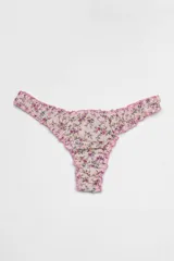 Pantie less color crema con estampado floral en tonos rosa y lila, con terminaciones de volados en color rosa.