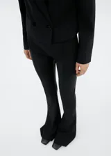 Pantalón negro acampanado de lana, con dos bolsillos de ribete en la parte delantera.