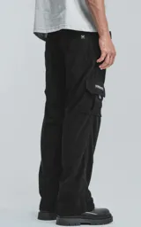 Pantalón cargo de pana negra, corte ancho y tiro alto con elástico en la cintura. Presenta bolsillos cargo amplios a los lados de las piernas, uno de ellos con un pequeño detalle de etiqueta o cierre.