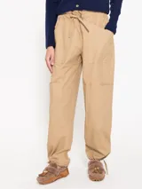 Babucha color beige confeccionada en gabardina lisa, con bolsillos cargo. Tiene ajuste de lazo en la cintura y en el ruedo.